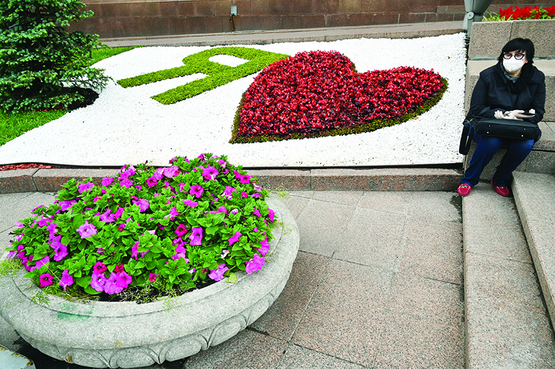 KIEV: A woman wearing a protective face mask and gloves as she rests near a flowerbed ‘I love’ in the center of Kiev, as Ukraine eases anti-virus restrictions imposed to curb the spread of the COVID-19 outbreak. — AFP