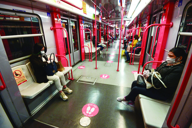TOPSHOT - Commuters sit in the metro where red circles on the ground indicate where to stand to maintain distance between people, on May 4, 2020 in Milan as Italy starts to ease its lockdown, during the country's lockdown aimed at curbing the spread of the COVID-19 infection, caused by the novel coronavirus. - Stir-crazy Italians will be free to stroll and visit relatives for the first time in nine weeks on May 4, 2020 as Europe's hardest-hit country eases back the world's longest nationwide coronavirus lockdown. (Photo by Miguel MEDINA / AFP)