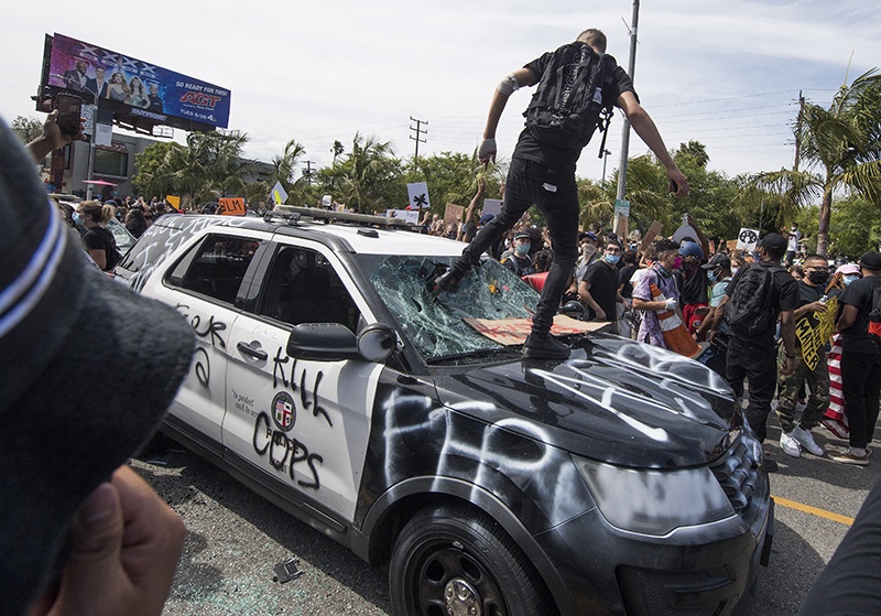 LOS ANGELES: Demonstrators smash a police vehicle in the Fairfax district as they protest the death of George Floyd on Saturday. – AFP (See Page 8)