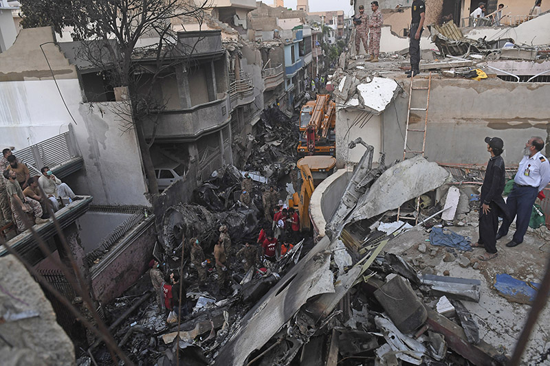 KARACHI: Security personnel search for victims in the wreckage of a Pakistan International Airlines aircraft after it crashed in a residential area on Friday. – AFP
