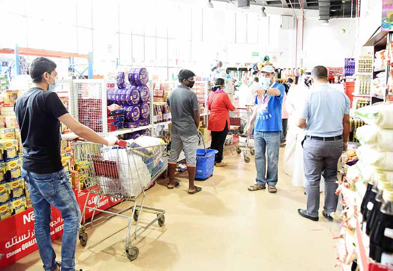 KUWAIT: In these May 8, 2020 file photos, volunteers organize queues inside and outside a co-op society in Kuwait. -- Photos by Fouad Al-Shaikh
