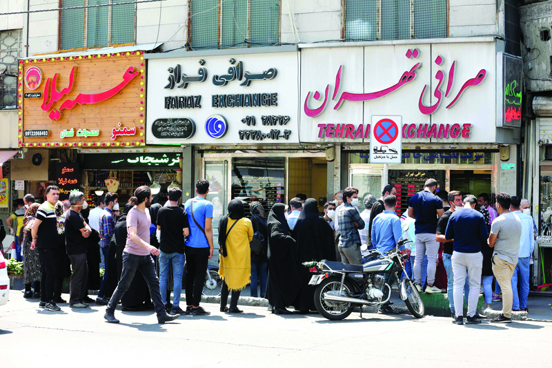 Iranians, wearing protective masks without observing social distancing, queue outside a money exchange office in the capital Tehran on May 9, 2020, during the coronavirus (COVID-19) pandemic. - While many residents in Iran's capital are taking advantange of loosened Covid-19 controls, some fear a renewed spike in deaths in what remains the Middle East's deadliest virus epicentre. (Photo by ATTA KENARE / AFP)