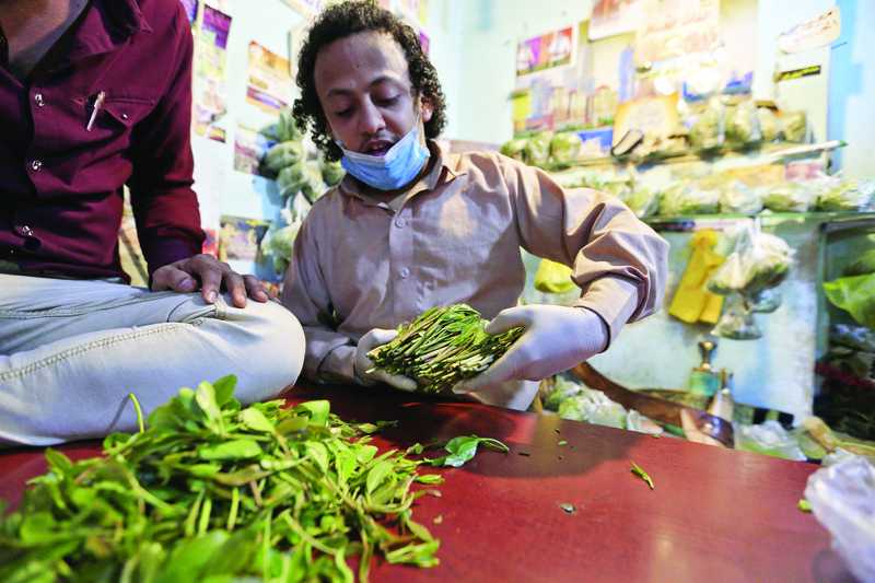 A Yemeni vendor sorts through leaves of qat, the ubiquitous mild narcotic, at a market in the capital Sanaa on May 1, 2020. - While most of the world's markets have closed to curb the spread of coronavirus, in Yemen's capital Sanaa, downtown districts selling qat -- the ubiquitous mild narcotic -- still bustle with people. Flouting social distancing rules, Yemenis jostle to select bunches of the chewable leaf from vendors packed into the narrow laneways crowded with stalls. (Photo by Mohammed HUWAIS / AFP)