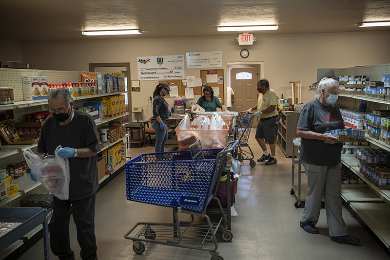 Volunteers prepare food packages at Jonah's House Food Pantry fills a bag of food on May 7, 2020 in Carlsbad, New Mexico. - Waiting for an upturn or pulling out, a dilemma faced in recent weeks by oil industry workers in Carlsbad, in the southwestern United States, where the sharp drop in oil prices has dealt a blow to the local economy. (Photo by Paul Ratje / AFP)