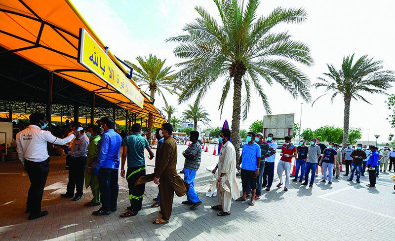 DUBAI: Laborers wearing protective masks queue in Dubai after authorities of the United Arab Emirates started to ease a national lockdown put in place to curb the spread of COVID-19 coronavirus. - AFP