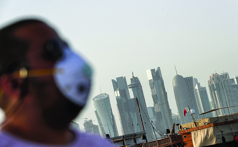 DOHA: In this photo taken on March 16, 2020, a man wearing a mask walks along the cornice. – AFP