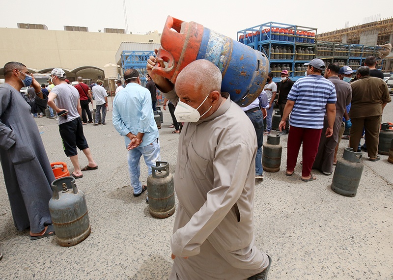 Paople queue in front of a shop to refill their gas cylinders in Kuwait City on May 10, 2020, a day after Kuwaiti authorities announced a 20-day total lockdown due to the COVID-19 pandemic. - The lockdown will be implemented from May 10 to 30, during which public sector tasks will be performed remotely while private sector activities are suspended except for essential functions, Kuwait's relevant authorities announced on Twitter. (Photo by YASSER AL-ZAYYAT / AFP)