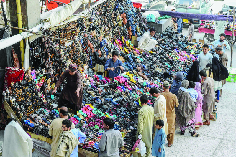 People shop for shoes near stall after the government eased the nationwide lockdown imposed as a preventive measure against the COVID-19 coronavirus, in Quetta on May 9, 2020. (Photo by Banaras KHAN / AFP)