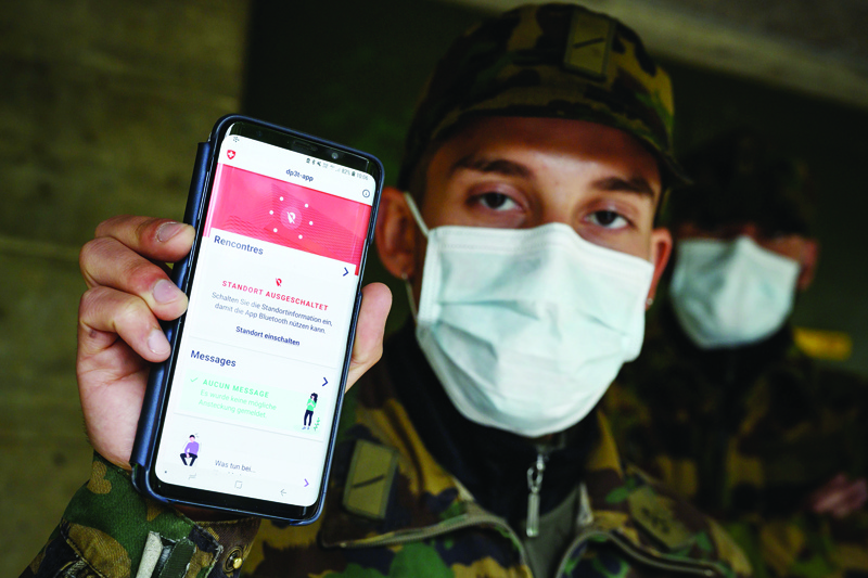 A Swiss soldier wearing a protective facemask poses with his smartphone, on April 30, 2020, at the Swiss army barracks of Chamblon, during field test of an app created by the Swiss Federal Institute of Technology Lausanne (EPFL) that could help trace those who have been in close contact with someone who tested positive for the COVID-19, caused by the novel coronavirus. - A unit of Swiss army conscripts are taking the fight to the coronavirus pandemic by helping to develop a Bluetooth-based smartphone app aimed at suppressing a resurgence of COVID-19. (Photo by Fabrice COFFRINI / AFP)