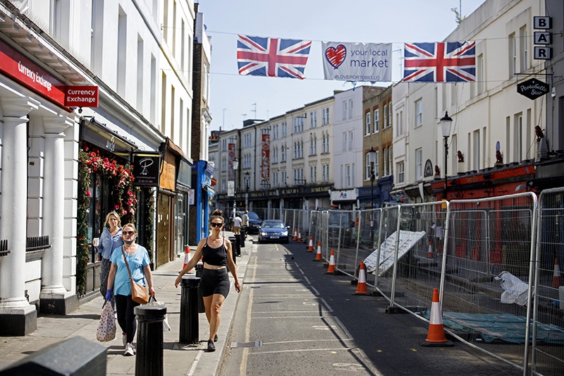LONDON: People walk past closed shops in Portobello Market in west London on Monday following the easing of the lockdown restrictions during the novel coronavirus pandemic. – AFP
