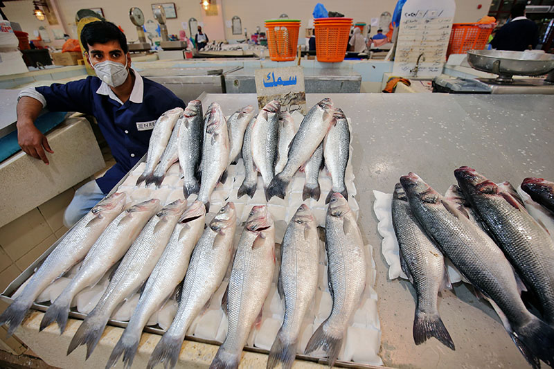 A mask-clad vendor waits for costumers at a fish market in Kuwait City on June 3, 2020. (Photo by YASSER AL-ZAYYAT / AFP)