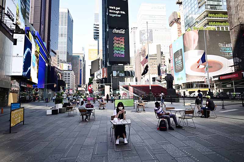 NEW YORK: People sit on tables , respecting social distancing at Times Square as New York City enters phase two of reopening. — AFP