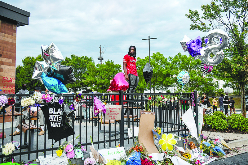 ATLANTA: A man stands on a table on a patio railing outside a burned Wendy’s restaurant on the third day, following Rayshard Brooks shooting death by police in the restaurant parking lot in Atlanta, Georgia. — AFP