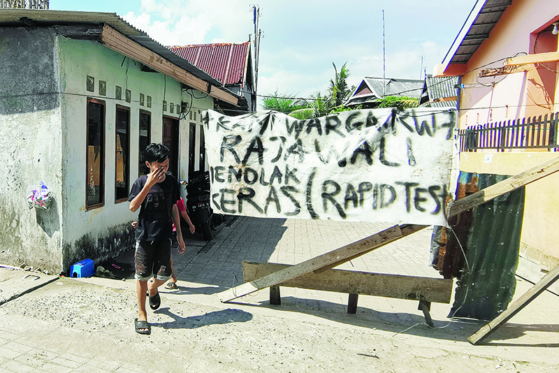 MAKASSAR: A villager stands next to a banner readings their rejection to the rapid test for their community members amid concern of the COVID-19 coronavirus, in Makassar, South Sulawesi. Dozens of Indonesians have been arrested for snatching COVID-19 victims from hospitals in a bid to bury them according to local customs in the Muslim majority nation. — AFP