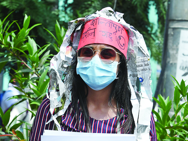 KATHMANDU: A protester holds a placard during a demonstration against the government’s handling of the fight against the COVID-19 coronavirus, in Kathmandu. –—AFP