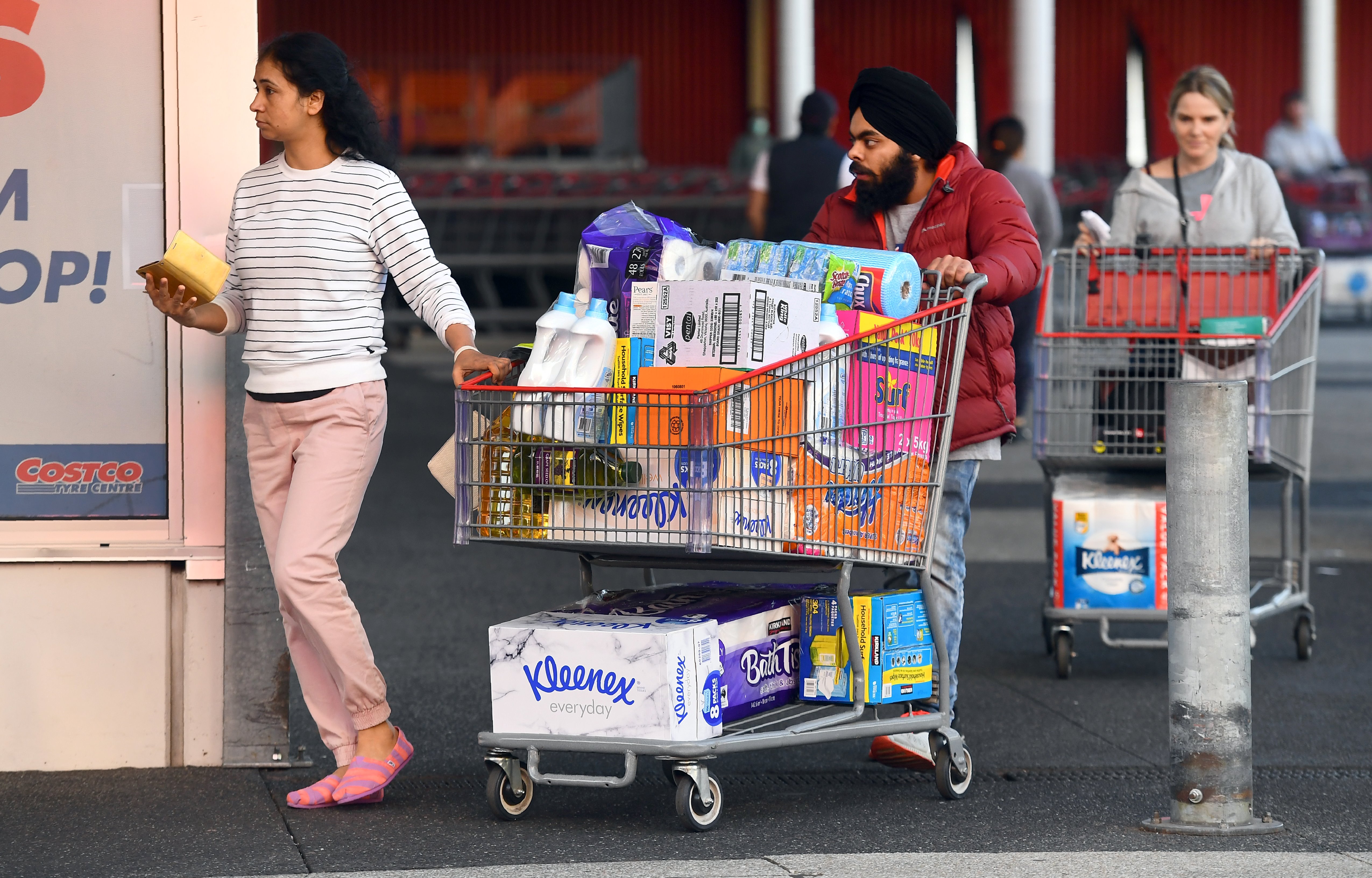 People leave a Costco outlet with a trolley full of toilet paper and cleaning products as fears of a second wave of COVID-19 have sparked a rush on some supermarket items in Melbourne on June 24, 2020. - Major supermarkets in the state of Victoria have reimposed buying limits on toilet paper and other essentials after a renewed escalation in demand sparked fears of a return to scenes of panic-buying seen early in the pandemic. (Photo by William WEST / AFP)