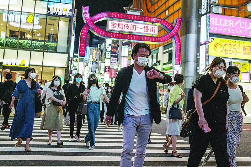 TOKYO: People wearing face masks walk across a street at Kabukicho district of Tokyo. Japan’s unemployment rate rose to 2.9 percent in May, official data showed yesterday. —AFP