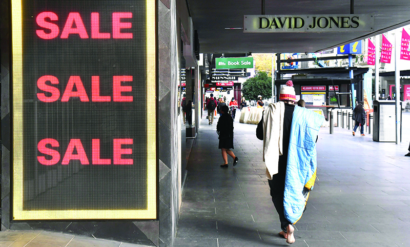 MELBOURNE: A homeless man walks past a sale sign in a store window in Melbourne’s central business district yesterday. Australia is heading for its first recession in nearly three decades after the economy shrunk in the January-March quarter.— AFP