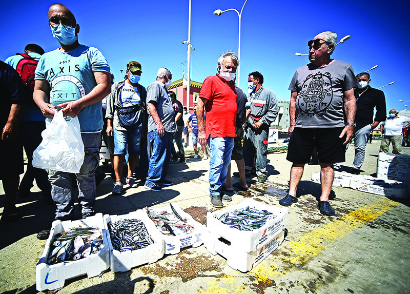 ROME: People gather to buy fishes directly off fishermen’s boats at the port of Fiumicino, west of Rome.  Across the world, consumers are emerging from lockdowns warier and more thrift-conscious than before.— AFP