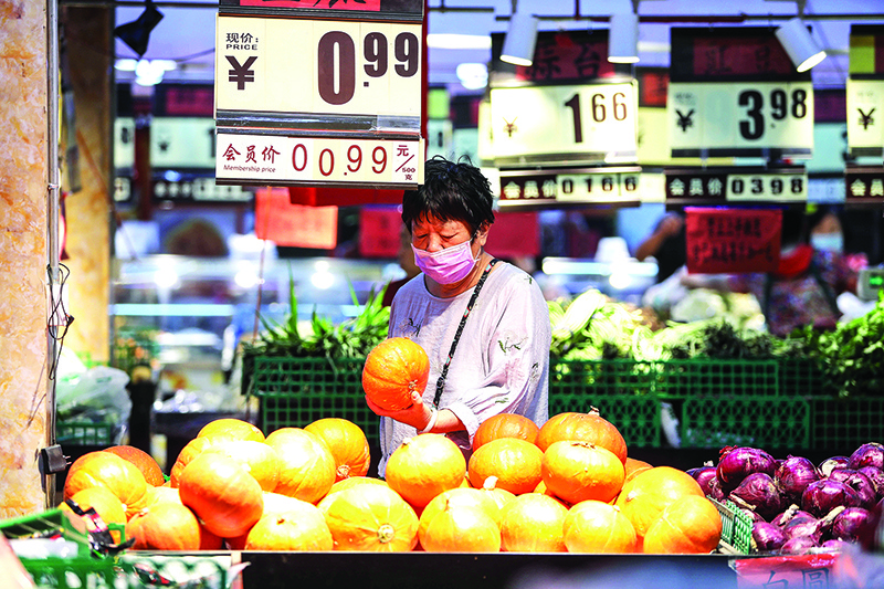 SHENYANG: A customer looks at a pumpkin at a market in Shenyang in China’s northeastern Liaoning province yesterday. China’s consumer price index (CPI) rose 2.4 percent in May, just below the 2.6 percent expected and easing from 3.3 percent a month earlier, according to data from the National Bureau of Statistics yesterday.—AFP
