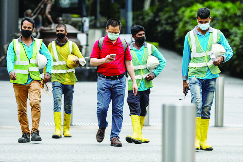 SINGAPORE: Migrant workers in essential services wearing safety vests cross a street at Orchard Road in Singapore. —Reuters