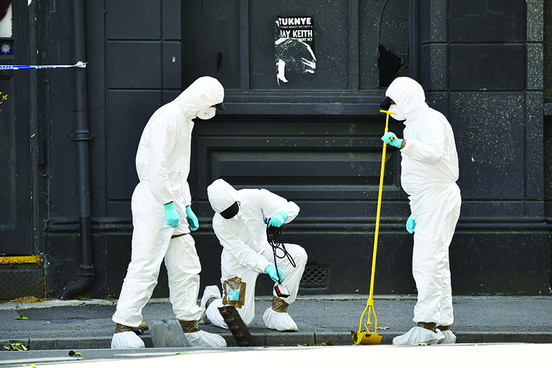 READING: Police forensics officers dressed in Tyvek protective PPE (personal protective equipment) suits and wearing masks, conduct a search of a drain near to Forbury Gardens park in Reading, west of London - the scene of the June 20 stabbing spree. –— AFP