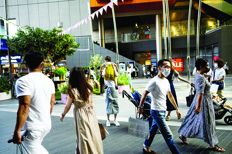 TOKYO: People wearing face masks amid concerns over the spread of coronavirus (COVID-19) walk at Futako Tamagawa neighborhood in Tokyo yesterday. — AFP