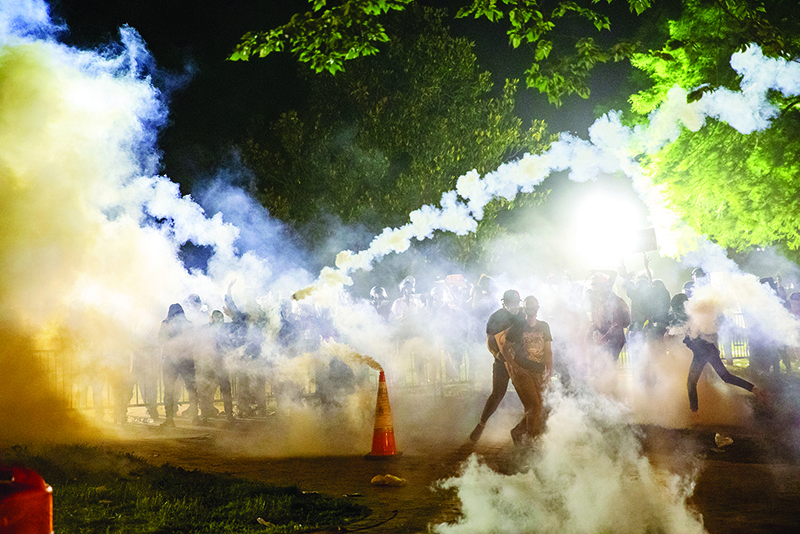 MINNEAPOLIS: Tear gas rises above as protesters face off with police during a demonstration outside the White House over the death of George Floyd at the hands of Minneapolis Police. — AFP