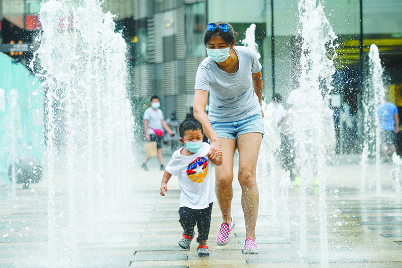 BEIJING: A woman and a child wearing face masks walk past a row of fountains in a business district in Beijing. China reported another 17 cases of the coronavirus, of which 14 were local cases in Beijing. — AFP