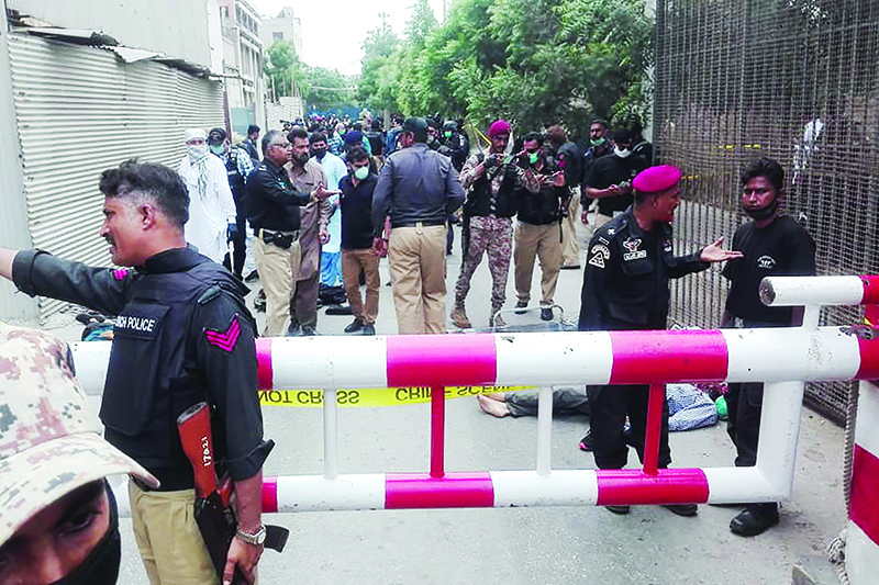 KARACHI: Policemen secure an area around a body outside the Pakistan Stock Exchange building yesterday. —  AFP