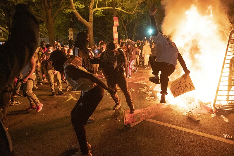 WASHINGTON: Protesters jump on a street sign near a burning barricade during a demonstration against the death of George Floyd near the White House on Sunday. – AFP