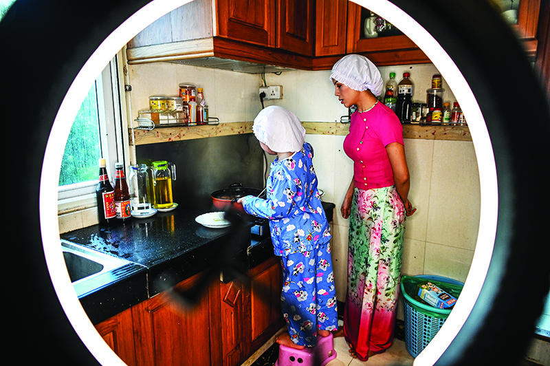 Moe Myint May Thu (left) and her mother Honey Cho filming a cooking video at their house in Yangon.