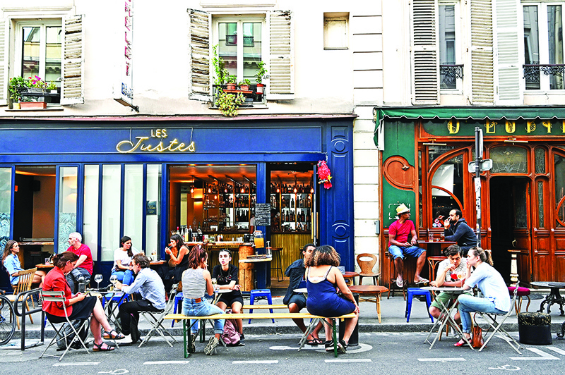 People eat and have drinks on restaurant and cafe terraces in Paris.