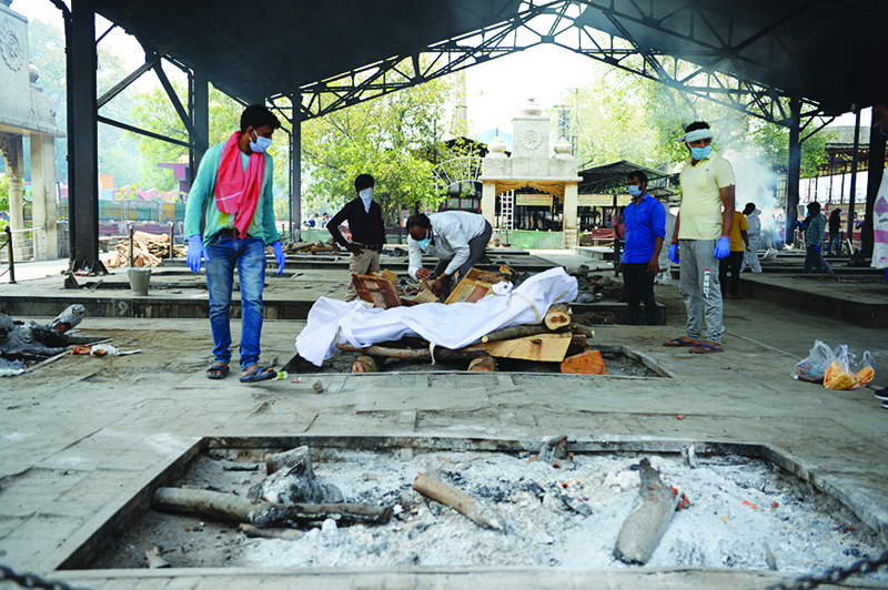 NEW DELHI: In this photograph, relatives prepare the cremation pyre for a person who died from the COVID-19 coronavirus, at the Nigambodh Ghat cremation ground in New Delhi. —AFP