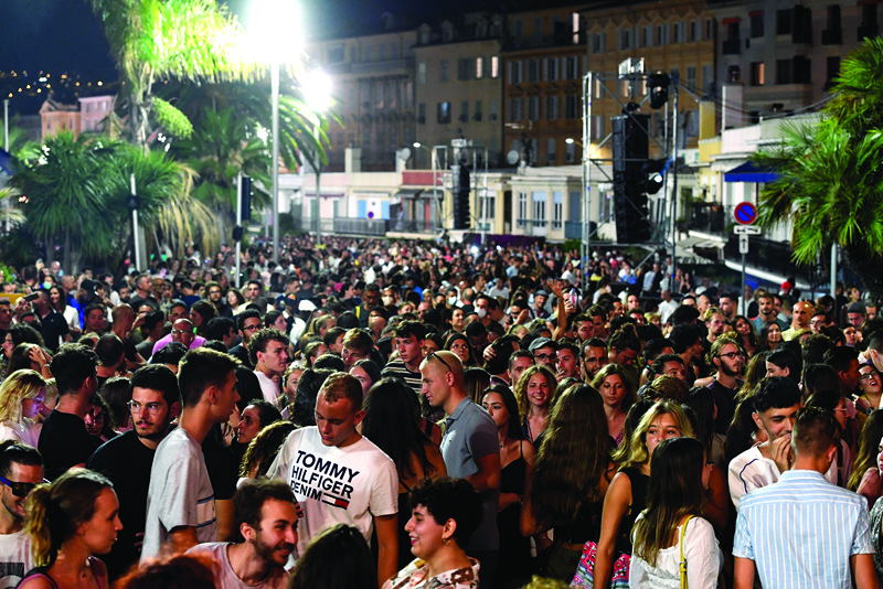People gather to listen to the set of French DJ and producer The Avener during a concert, the first public show in Nice since the shutdown due to the novel coronavirus, to celebrate the end of the health emergency on July 11, 2020, in Nice, southern France. (Photo by YANN COATSALIOU / AFP)