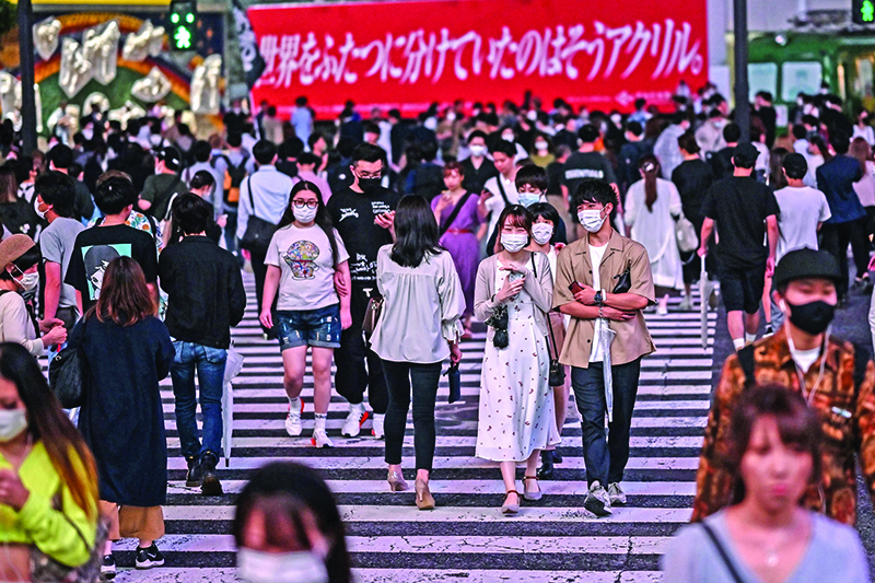 TOKYO: People wearing face masks cross a street in Tokyo. Tokyo is on its highest coronavirus alert level after a spike in new cases as experts said the rising infections were a clear ‘red flag’. — AFP