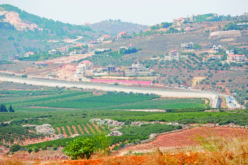 A picture taken from the northern Israeli town of Metula shows the southern Lebanese village of Kfar Kila behind the concrete barrier wall along the border between the two countries, on July 28, 2020. - Israel said it had repelled an attempt by Hezbollah fighters to penetrate its northern border on July 27, but the Lebanese group denied any involvement in the incident.  nThe border clash, which Israel said included an exchange of fire between its troops and gunmen, followed days of reported heightened tensions between Hezbollah and the Jewish state. (Photo by JALAA MAREY / AFP)