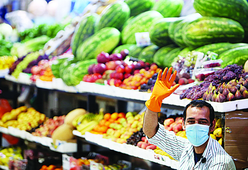 A fruit vendor wearing a face mask waves for the camera as he waits for clients at a market in Kuwait City, on July 20, 2020 amid the Covid-19 coronavirus pandemic crisis. (Photo by YASSER AL-ZAYYAT / AFP)