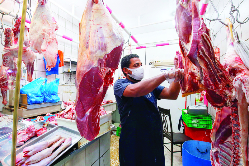 A butcher, wearing a protective due to the COVID-19 pandemic, cuts meat at his shop in Kuwait City on July 7, 2020. (Photo by YASSER AL-ZAYYAT / AFP)