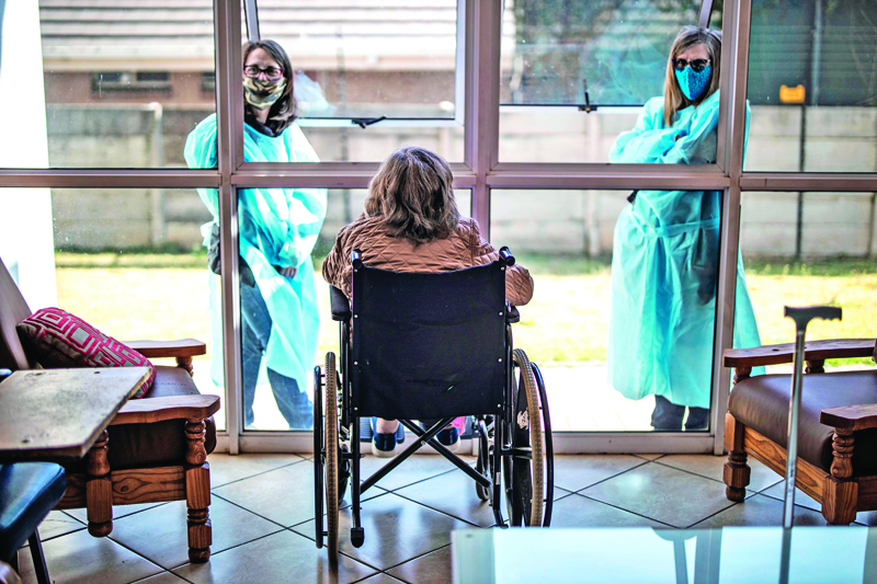Relatives chat through a window to a wheelchair bound woman, a resident of Casa Serena, an Old Age home in Johannesburg, on July 22, 2020. - Senior residents of the old age home Casa Serena in Johannesburg are devastated by a rigid COVID-19 coronavirus quarantine, following a deadly spike in cases inside the institution.nAt least 17 facilities were affected by COVID-19 coronavirus in the Gauteng province. (Photo by MARCO LONGARI / AFP)