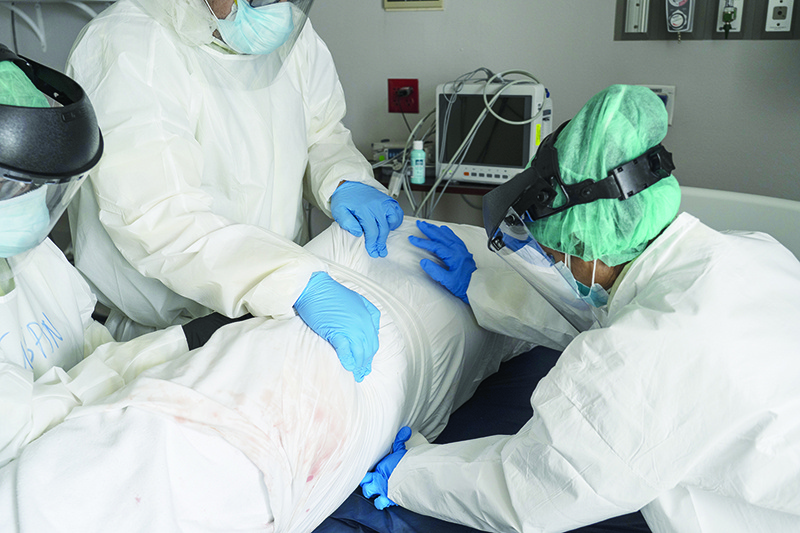 HOUSTON, TX - JUNE 30: (EDITORIAL USE ONLY) Medical staff wearing full PPE wrap a deceased patient with bed sheets and a body bag in the Covid-19 intensive care unit at the United Memorial Medical Center on June 30, 2020 in Houston, Texas. Covid-19 cases and hospitalizations have spiked since Texas reopened, pushing intensive-care wards to full capacity and sparking concerns about a surge in fatalities as the virus spreads.   Go Nakamura/Getty Images/AFP