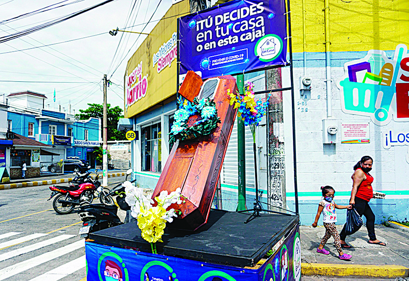 ESCUINTLA: A woman and her daughter walk by a coffin with a sign reading ‘You decide, at home or in this box’, in the streets of Escuintla municipality, 55 km south of Guatemala City, during a local authorities’ campaign to stop the COVID-19 coronavirus pandemic. —AFP