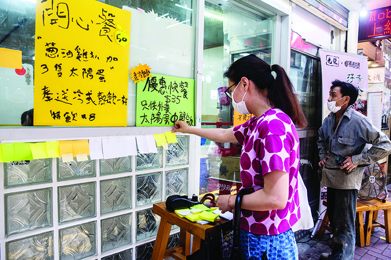 HONG KONG: A woman sticks a blank note onto a ‘Lennon Wall’ outside a pro-democracy restaurant in Hong Kong in response to a new national security law introduced in the city which makes political views, slogans and signs advocating Hong Kong’s independence or liberation illegal. — AFP