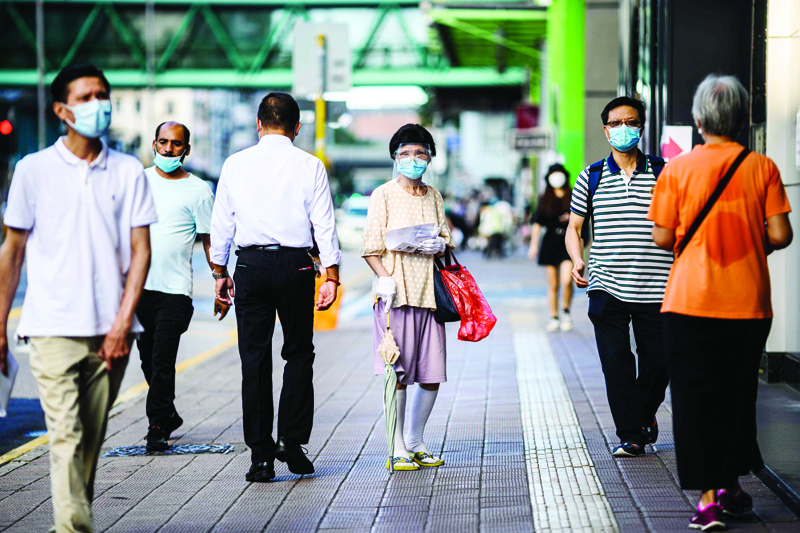 Pedestrians wear face masks in the Kowloon-side Sham Shui Po district of Hong Kong in the early morning of July 29, 2020, as new social distancing measures come into effect which include having to wear masks in public, to combat a new wave of coronavirus infections. (Photo by ANTHONY WALLACE / AFP)