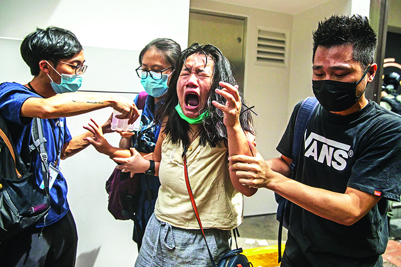 HONG KONG: A woman reacts after she was hit with pepper spray deployed by police as they cleared a street with protesters rallying against a new national security law in Hong Kong yesterday. — AFP