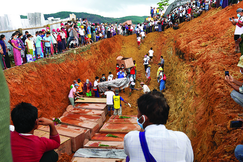 HPAKANT: Volunteers bury bodies of miners in a mass grave while relatives look on during a funeral ceremony near Hpakant in Kachin state. — AFP