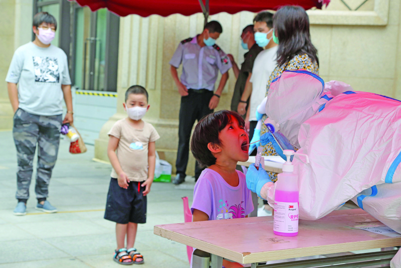 A health worker carries out a COVID-19 coronavirus test on a child at a makeshift testing center in Dalian, in China's northeast Liaoning province on July 27, 2020. - China recorded 61 new coronavirus cases on July 27 -- the highest daily figure since April -- propelled by clusters in three separate regions that have sparked fears of a fresh wave. (Photo by STR / AFP) / China OUT
