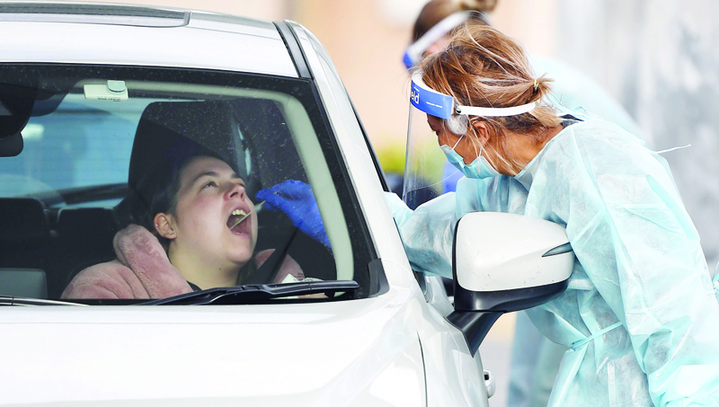 Members of the Australian Defence Force take a swab sample at a drive-through COVID-19 coronavirus testing station in the Melbourne suburb of Fawkner on July 2, 2020. - Around 300,000 people in Melbourne have to return to lockdown under the threat of fines and arrest as Australiaís second biggest city attempts to control a spike in virus cases. Health workers went door-to-door in the 36 Melbourne neighbourhoods targeted for lockdown, urging residents to be tested for the coronavirus. (Photo by William WEST / AFP)