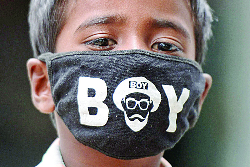 MEDAK: A boy wearing a facemask as a preventive measure against the spread of the COVID-19 coronavirus, looks on near a paddy field in Medak district of Telangana state yesterday. —AFP