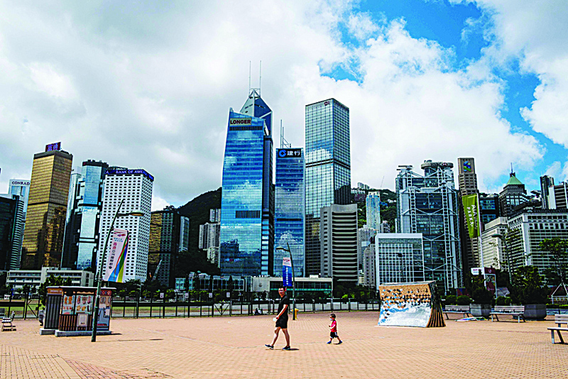 A man walks with his child past a view of commercial buildings in Hong Kong on July 16, 2020. - Beijing's tough new security law and President Donald Trump's order to rescind special trading privileges have blunted Hong Kong's competitive edge and risk turning the finance hub into just another Chinese city, analysts warn. (Photo by Anthony WALLACE / AFP) / TO GO WITH HongKong-China-politics-economy-US,FOCUS by Jerome Taylor and Su Xinqi